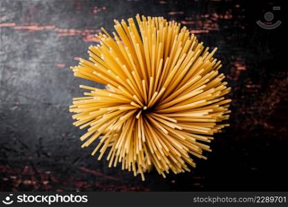 Not cooked spaghetti dry. Against a dark background. High quality photo. Not cooked spaghetti dry. Against a dark background.