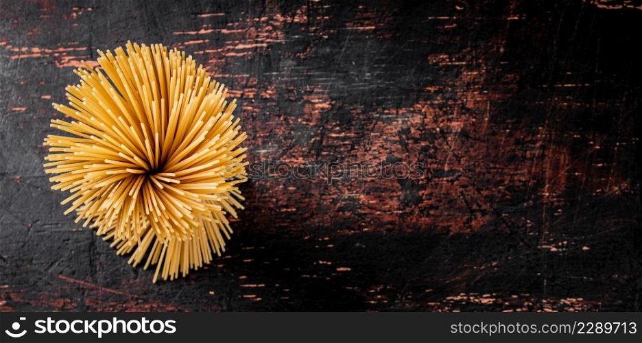 Not cooked spaghetti dry. Against a dark background. High quality photo. Not cooked spaghetti dry. Against a dark background.