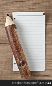 note and pencil on wooden background