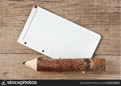 note and pencil on wooden background