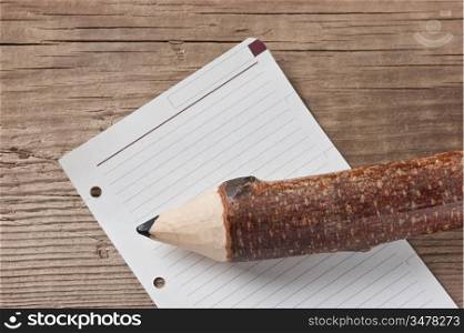 note and pencil on wooden background