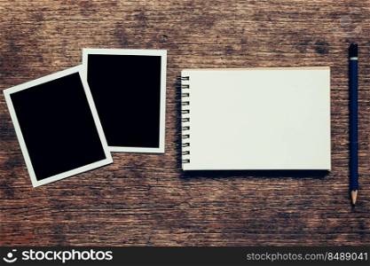 Note book and Photo frame on wood background.