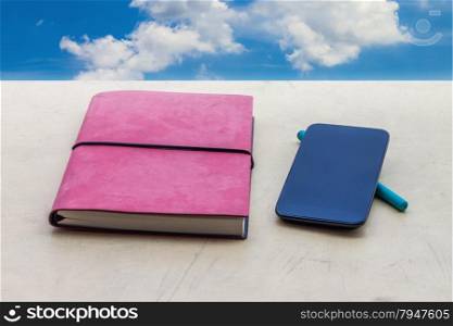 Note book and smartphoneon wall with blue sky,concept for technology and knowledge
