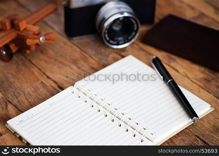 Note book and Travel vacation items on wooden table