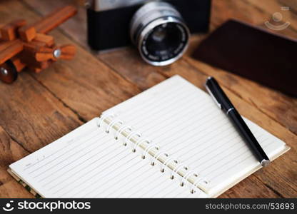 Note book and Travel vacation items on wooden table