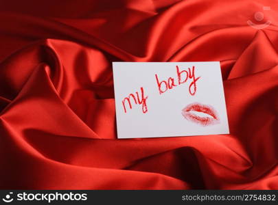 "Note on red silk. With an inscription " My baby " and a print of lips. Drawn by lipstick"
