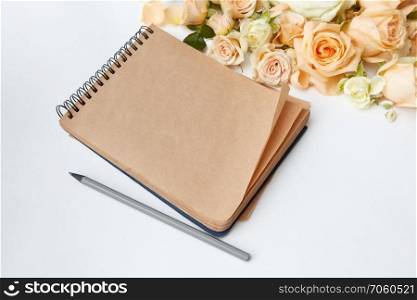 note pad with pen and beautiful bouquet on a white background ,. Roses buds as heart