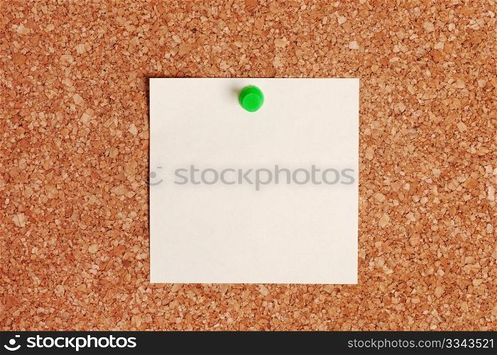 Note paper with push pin on corkboard.