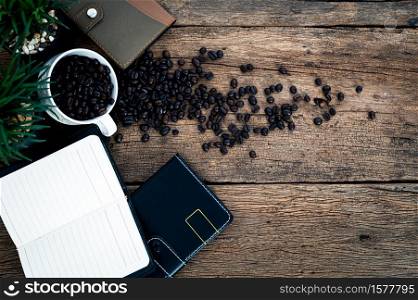 notebook and a mug of coffee beans on the table top view