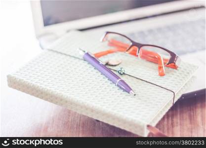 Notebook and eyeglasses with computer on wooden table, stock photo