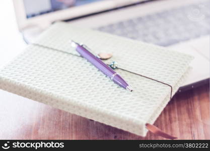 Notebook and pen with computer on wooden table, stock photo