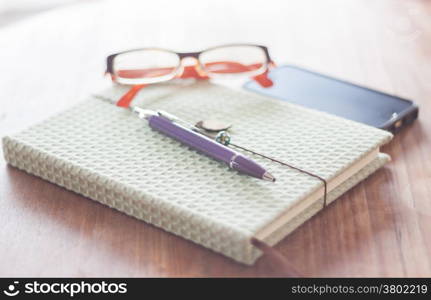 Notebook and pen with eyeglasses on wooden table, stock photo