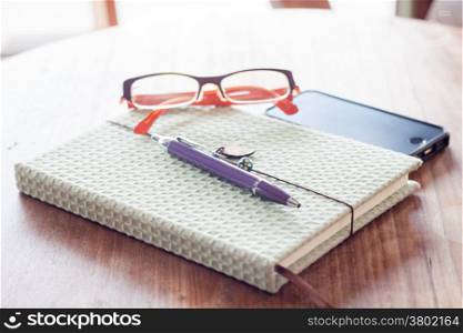 Notebook and pen with smartphone on wooden table, stock photo