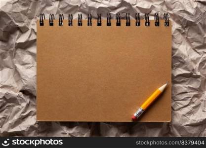 Notebook and pencil at parcel paper as background texture. Recycling concept or creative idea