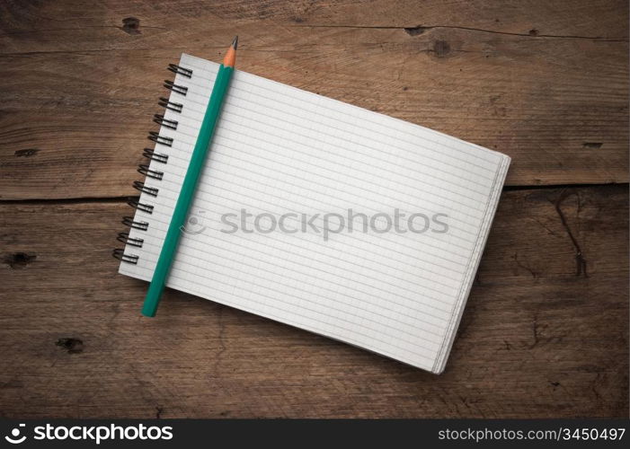 notebook and pencil on a wooden background