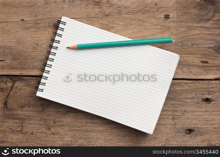 notebook and pencil on a wooden background