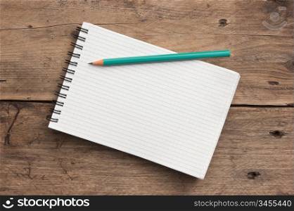notebook and pencil on a wooden background