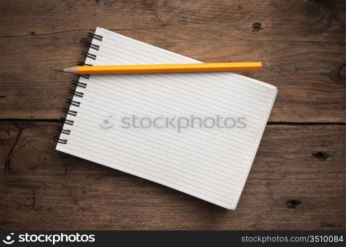 notebook and pencil on a wooden background