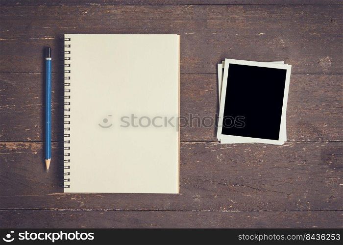 notebook and pencil with frame photo on wood table background with space