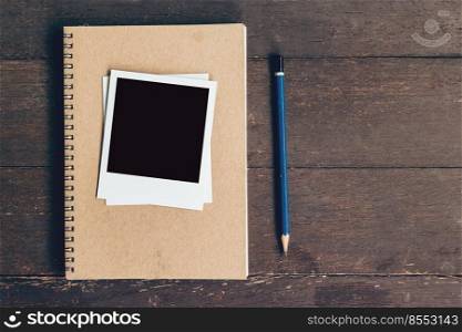 notebook and pencil with frame photo on wood table background with space