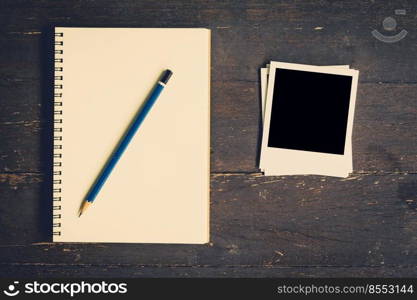 notebook and pencil with frame photo on wood table background with space