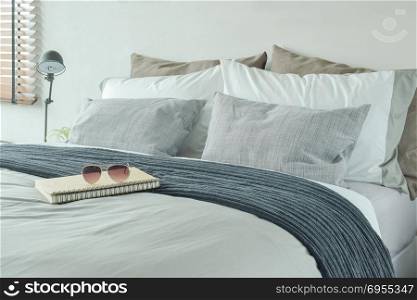 Notebook and sunglasses on bed with pillows