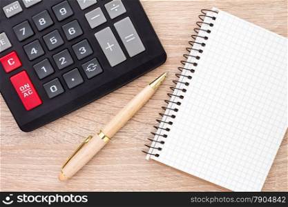 Notebook, ballpen and calculator on wooden desk