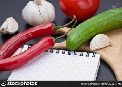 notebook for cooking recipes and vegetables on a cutting board