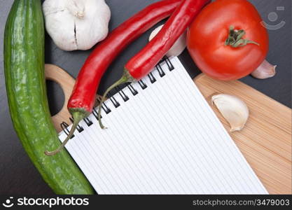 notebook for cooking recipes and vegetables on a cutting board