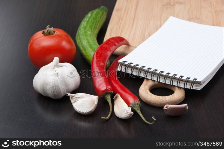 notebook for cooking recipes and vegetables on a cutting board