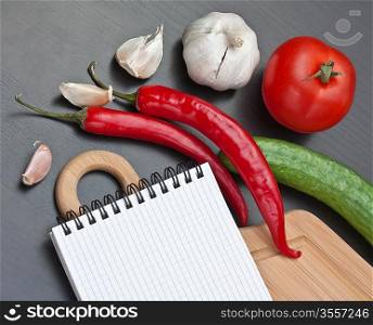 notebook for cooking recipes and vegetables on a cutting board