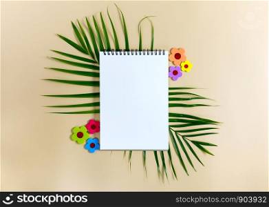Notebook for mock up with green leaves of palm tree on bright background