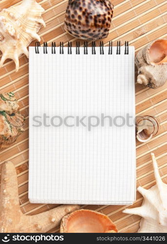 notebook on the background of mats and sea shells