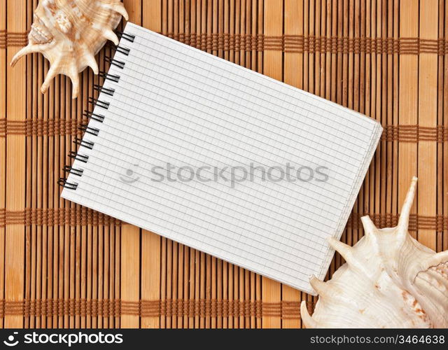 notebook on the background of mats and sea shells