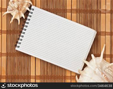 notebook on the background of mats and sea shells