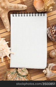 notebook on the background of mats and sea shells