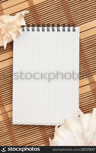 notebook on the background of mats and sea shells