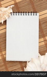 notebook on the background of mats and sea shells