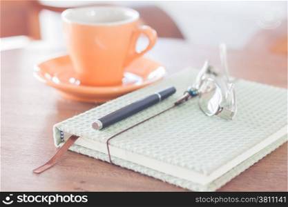 Notebook, pen and eyeglasses with orange coffee cup, stock photo