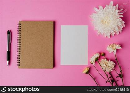 notebook, pen, blank card and flower on pink background