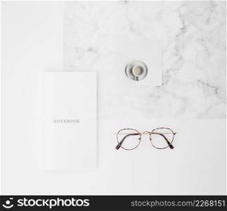 notebook text paper coffee cup eyeglasses white texture backdrop