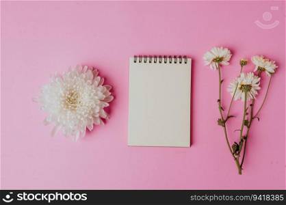 notebook with flower on pink background