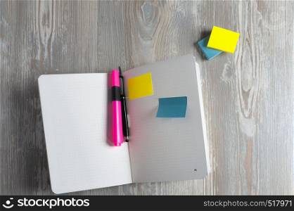 Notebook with pen and sticky notes on wood table