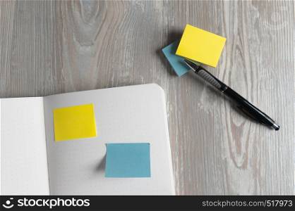 Notebook with pen and sticky notes on wood table