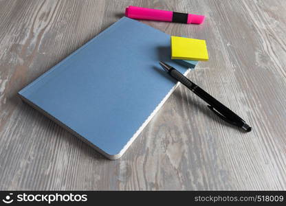 Notebook with pen and sticky notes on wood table