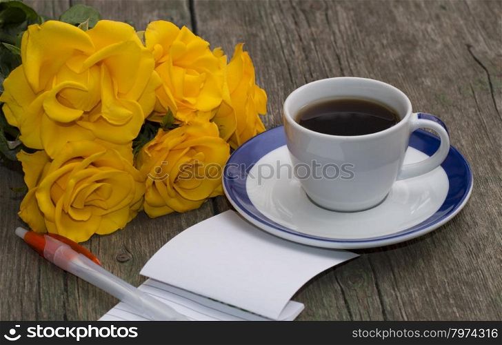 notebook with the handle, coffee and a bouquet of bright yellow roses