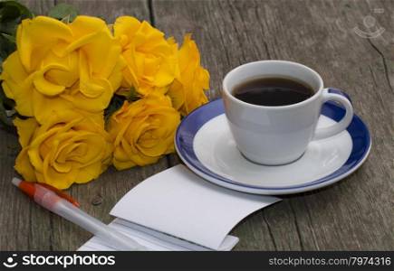 notebook with the handle, coffee and a bouquet of bright yellow roses