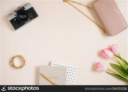 Notebooks and a bouquet of pink tulip flowers, a bag, a camera. Workplace of a female travel blogger. Flat lay, top view, copy space