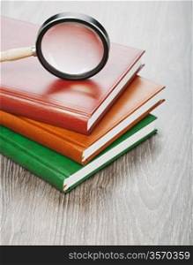 notebooks and magnifier on wooden background