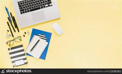 notebooks laptop with stationeries colored backdrop